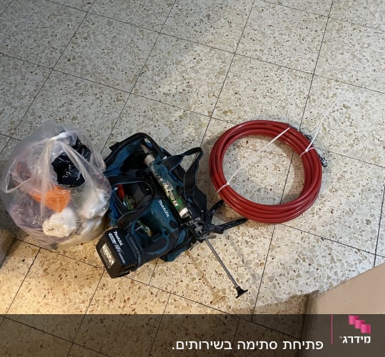 כלי עבודה וצינור אדום על רצפה מרוצפת